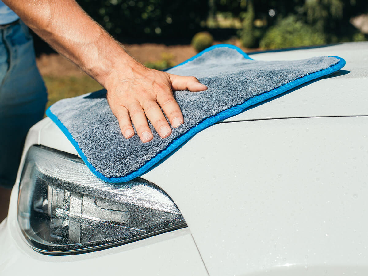 Weißes Auto wird mit Mikrofaser Trockentuch getrocknet 